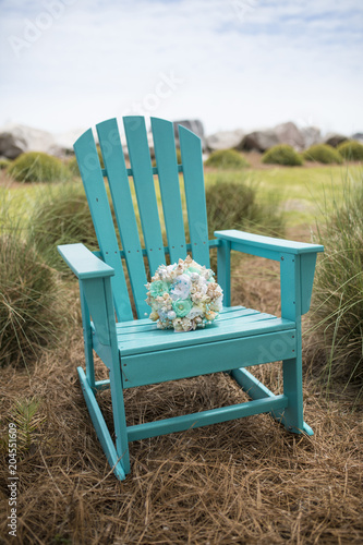 Bridal bouquet with sea shells on adirondack chair.