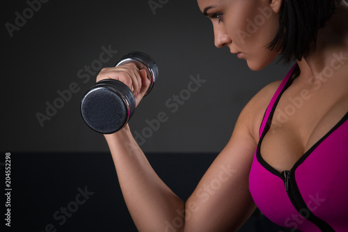 fitness model brunette holding weights on black background
