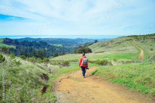 Hiker in red jacket with backpack on trail in beautiful landscape