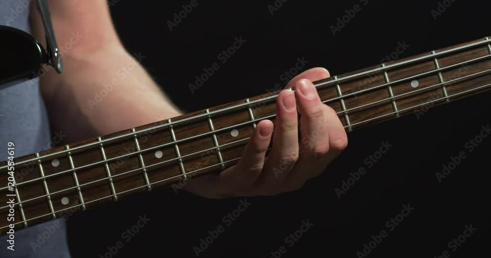 Fingers playing on the fretboard of a bass guitar Fingers playing on the fretboard of a bass guitar