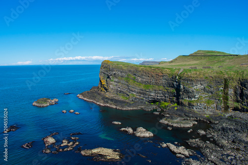 view on cliffs and ocean coast of northern ireland. volcanic rock formation on edge of water. blue sky and sunny day 