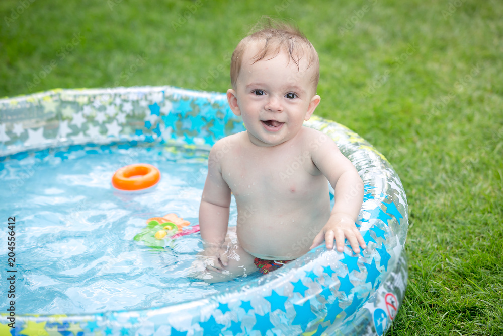 Portrait of cheerful smiling baby boy sitting in inflatable swimming pool at garden Portrait of cheerful smiling baby boy sitting in inflatable swimming pool at garden