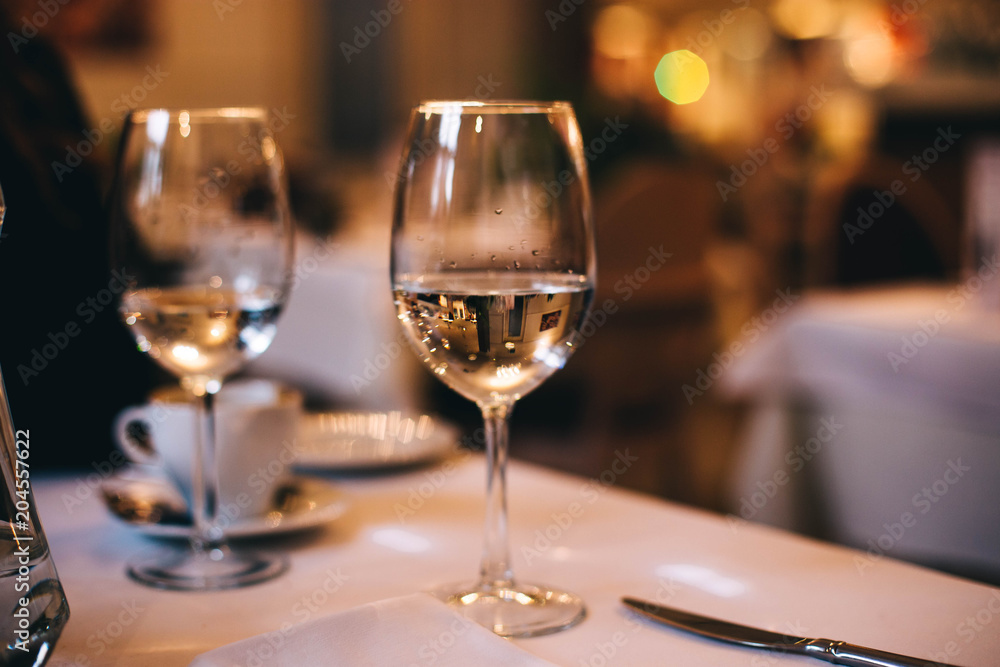 glass in the evening on the table in the restaurant. concept of a lonely date. glass in the evening on the table in the restaurant. concept of a lonely date.