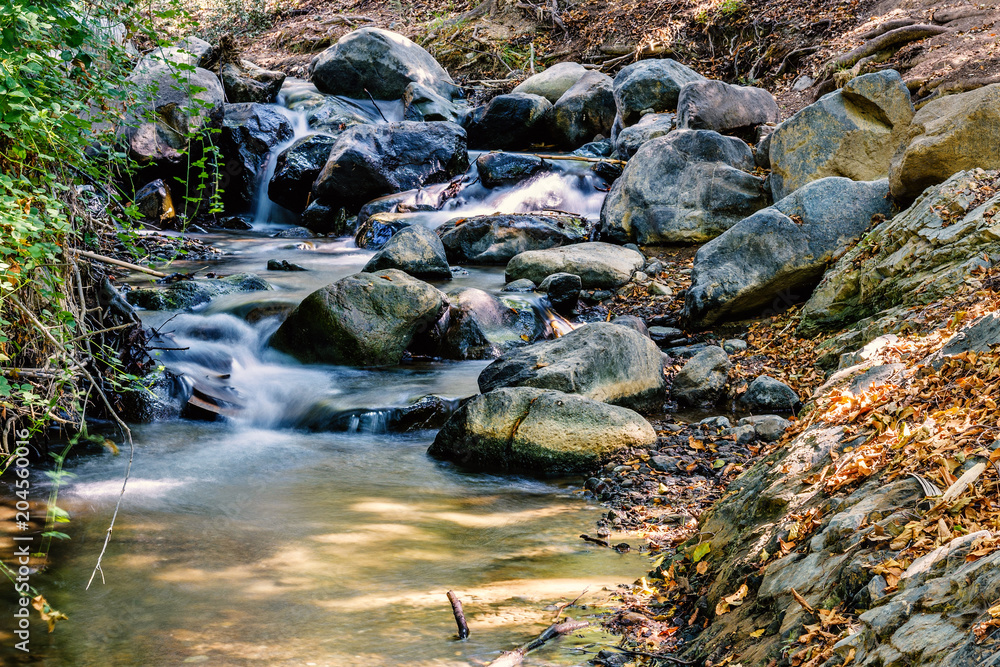 Daylight view to little river smoothly flowing through rocks Daylight view to little river smoothly flowing through rocks