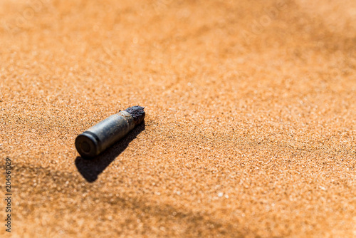 Old rusty cartridge case in sand close
