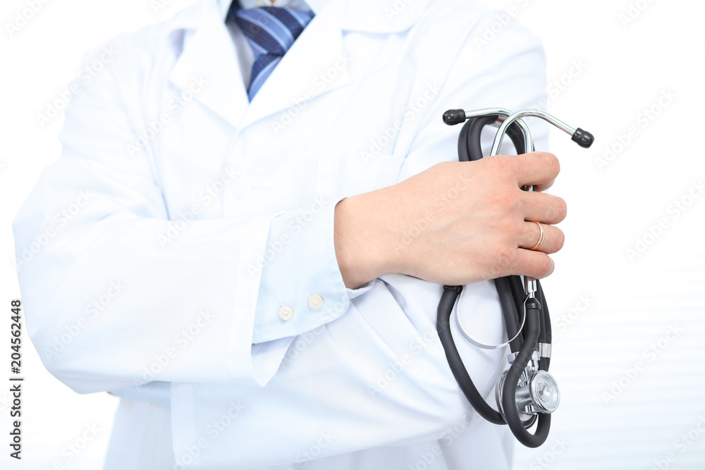 Close Up of Unknown male doctor standing straight while holding stethoscope. Medicine and health care concept Close Up of Unknown male doctor standing straight while holding stethoscope. Medicine and health care concept