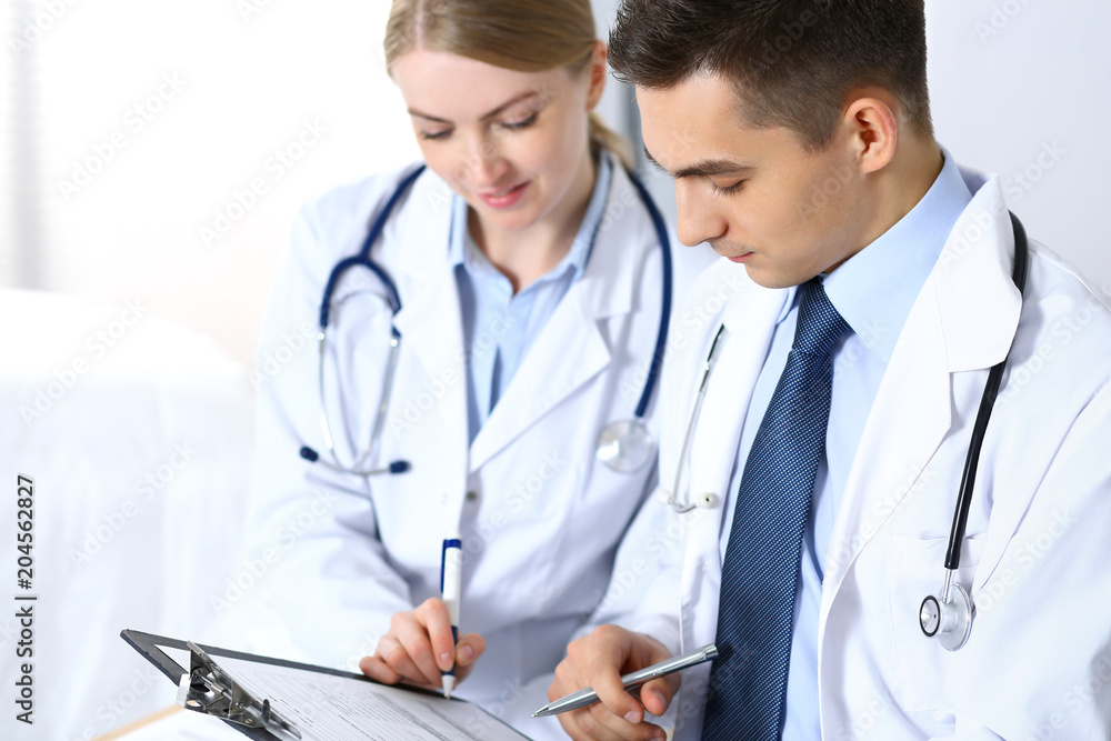 Doctors writing papers using clipboard. Physicians discussing medication program or studying at medical conference. Healthcare, insurance and medicine concept