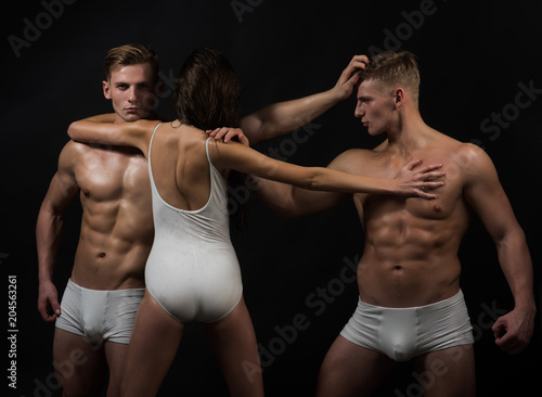 Twins men with muscular body and girl coach. Circus gymnasts at pilates or yoga training. Fitness and dieting. Flexibility in acrobatics. Gymnastic school and energy. Sport people or team work. © Volodymyr