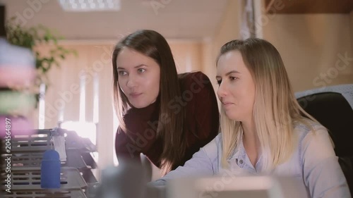 Carier start. A girl trainee in the office asks for help from a colleague.