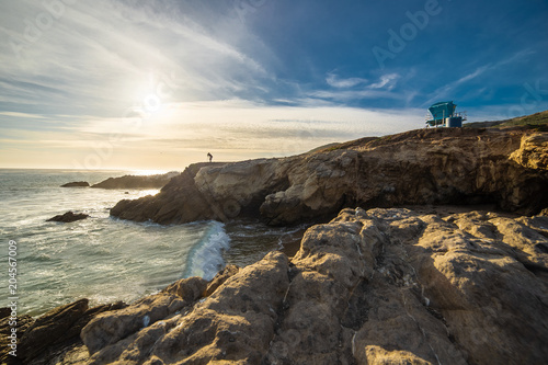 Silhouette of a landscape photographer standing on the rocks along the Malibu beach coastline in California during sunset.  The image depicts an HDR image of the ocean and nature. © Innovated Captures