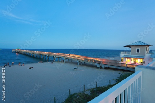 North Side of Deerfield Beach, Florida Pier Lit Up, Illuminated with Clear Blue Sky and Wispy Clouds Overhead in Twilight