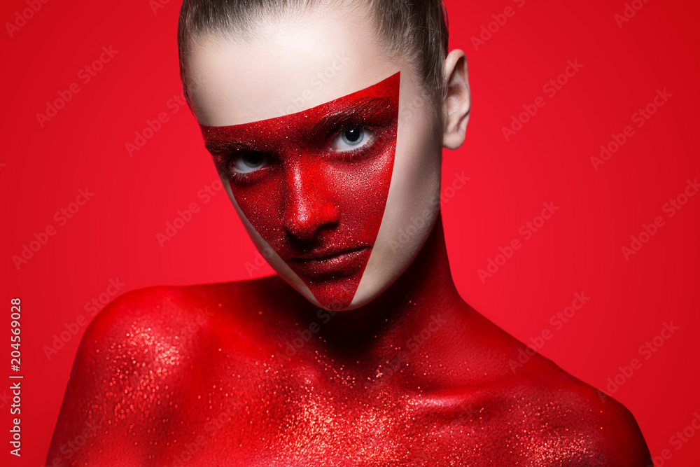 portrait of a girl on a red background. The triangle on the face and  shoulders painted red paint with glitter. Stock Photo