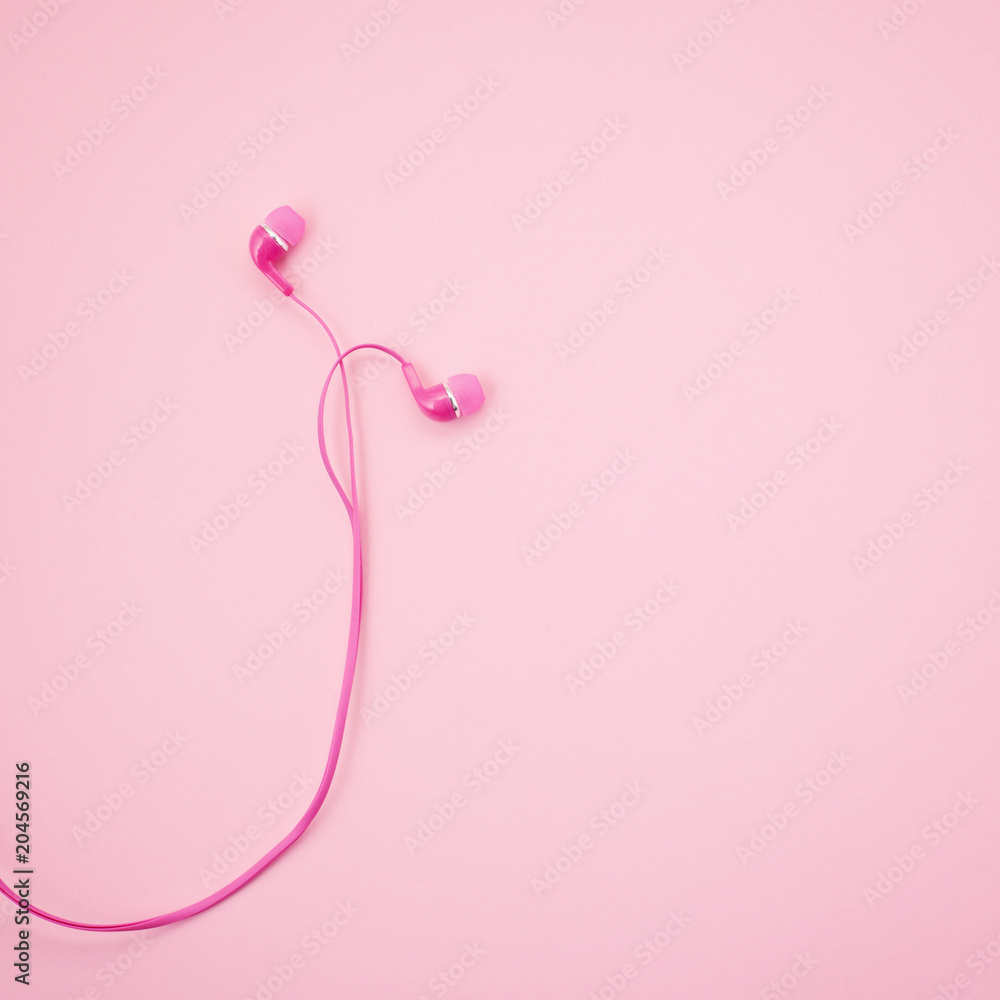 Top view of pink earphones on pink background.