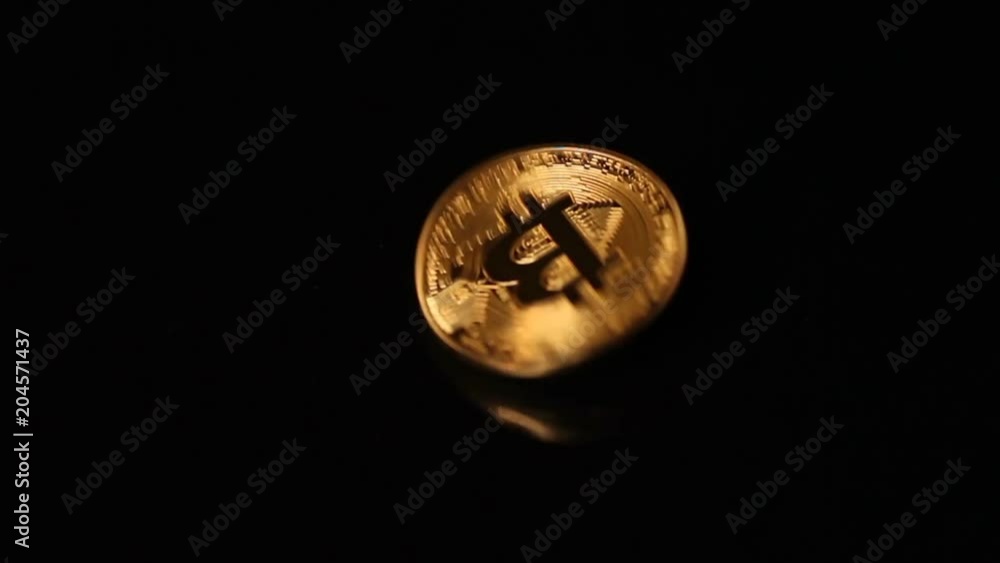 Gold bitcoin coin falls on black background with reflection Gold bitcoin coin falls on black background with reflection