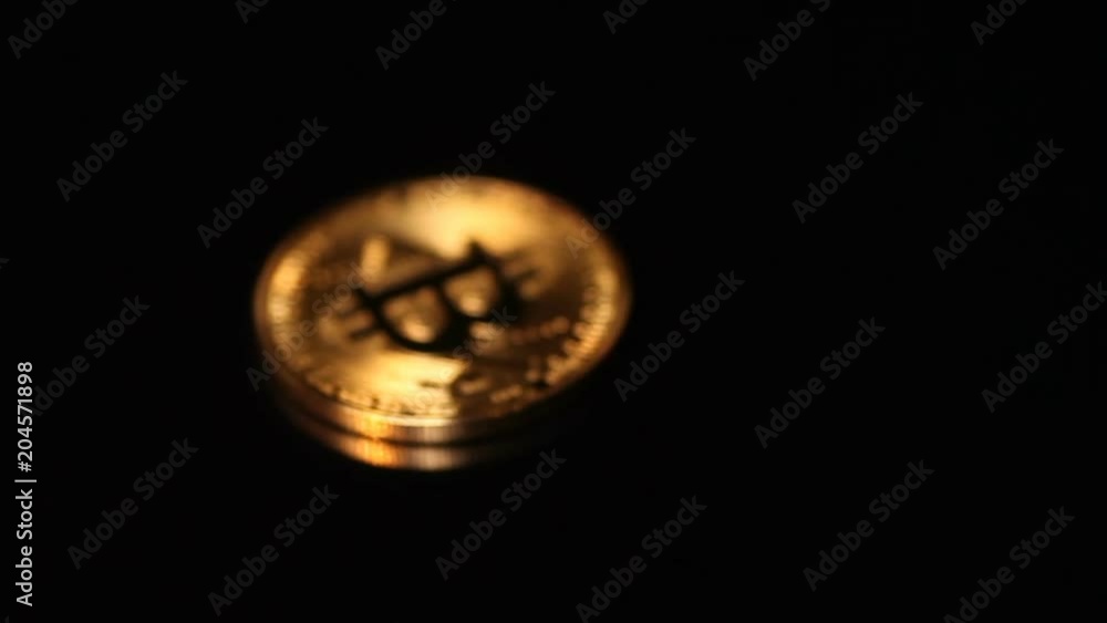 Gold bitcoin coin in focus and defocus on black background with reflection Gold bitcoin coin in focus and defocus on black background with reflection