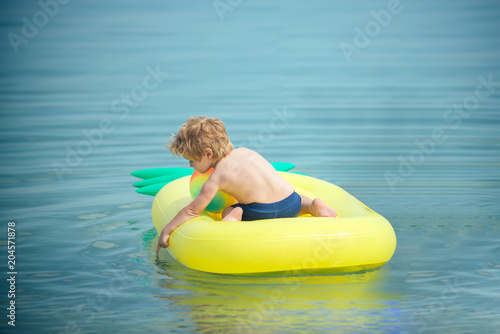 little kid on Caribbean sea in Bahamas. little kid swim on yellow onflatable mattress in sea water.