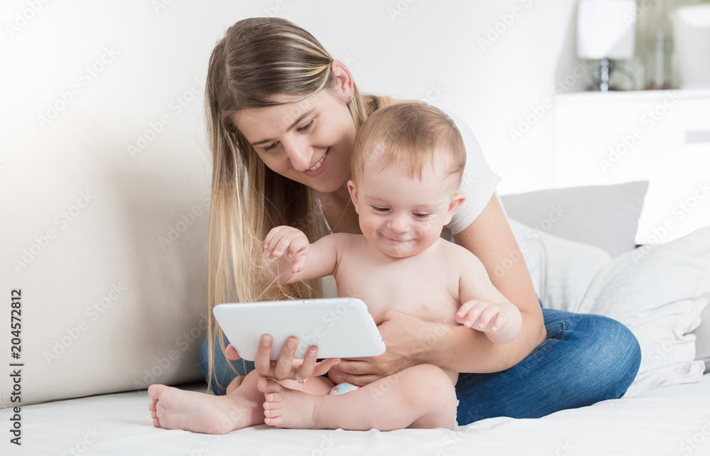 Portrait of smiling young mother watching movie on tablet computer with her baby son Portrait of smiling young mother watching movie on tablet computer with her baby son