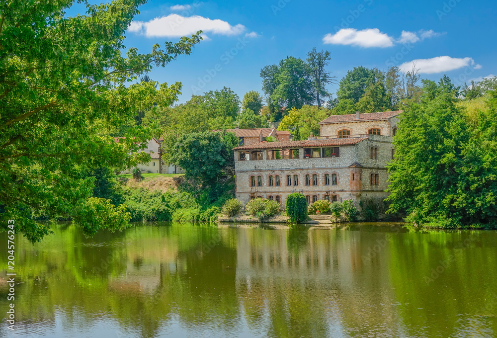 Lavaur, Midi Pyrenees, France - August 4, 2017: Old French style villa on the river bank under a blue summer sky Lavaur, Midi Pyrenees, France - August 4, 2017: Old French style villa on the river bank under a blue summer sky