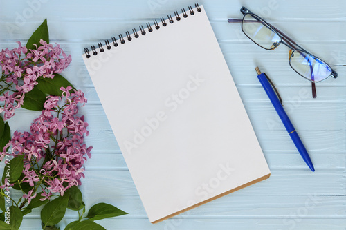  copy spaсe, notebook, pen, spectacles and branch of lilac on a blue tree background