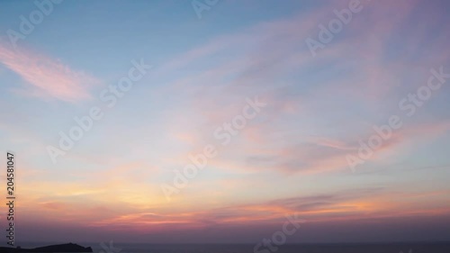 Small clouds float across a beautiful sky as the sun sets (HD)
