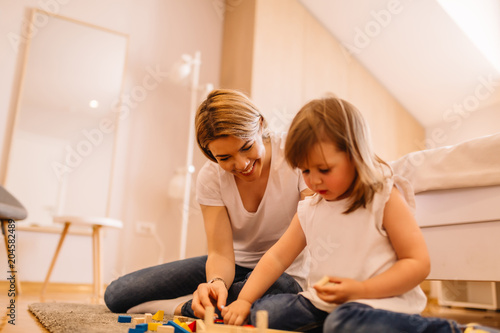 Mother and daughter playing with toys together on a floor