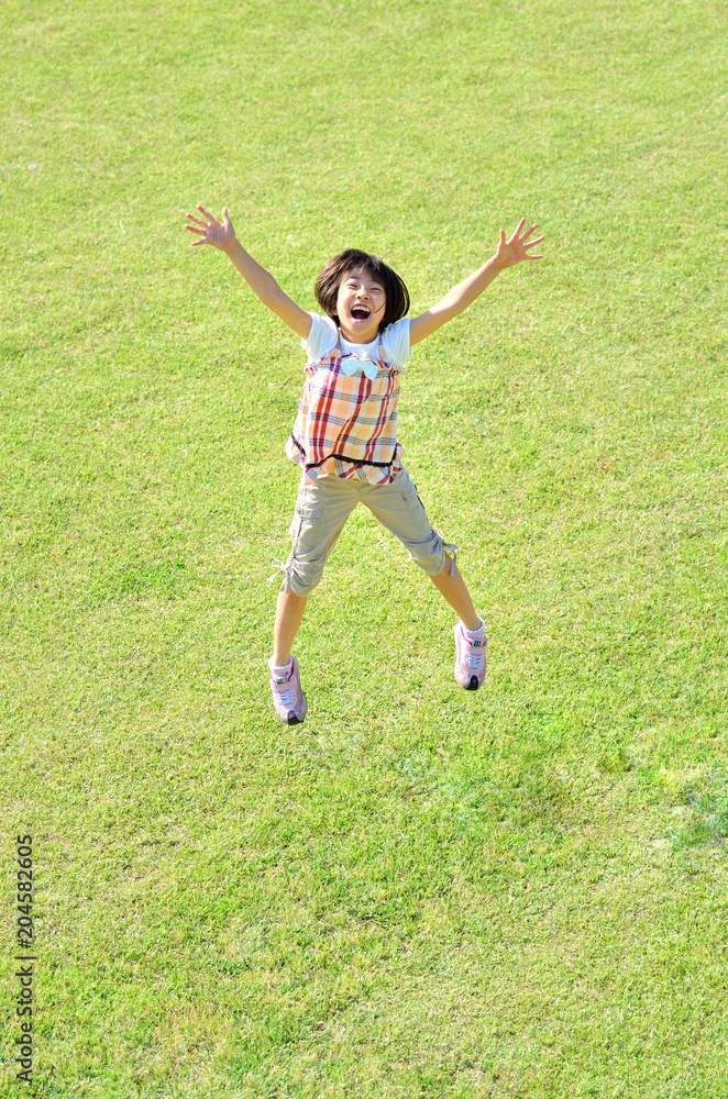 芝生広場でジャンプする女の子