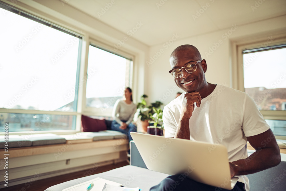 Fototapeta premium Smiling African businessman working online with colleagues in th