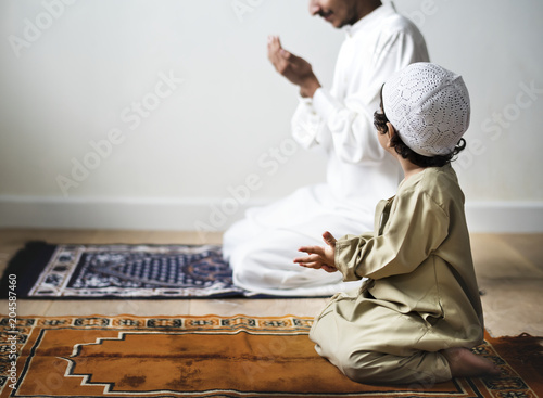 Little boy praying alongside his father during Ramadan