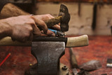 Man working in carpentry workshop. He attaches leather winding on wooden handle of an ax. Men at work. Hand work.