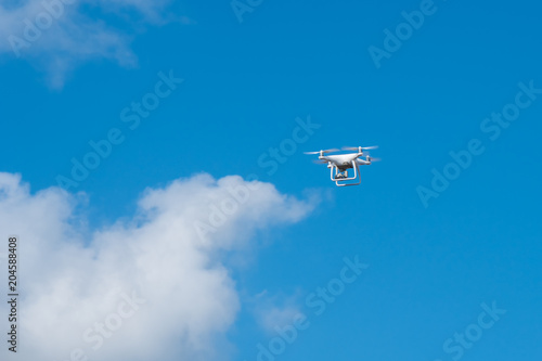 white drone hovering in a bright blue sky, Radio control helicopter with camera