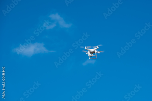 Fototapeta Naklejka Na Ścianę i Meble -  white drone hovering in a bright blue sky, Radio control helicopter with camera