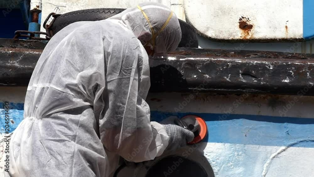 Working people tear off paint on metal in repairs process at shipyard. Workers in overalls reconstruct at ship repair yard outdoors in port. Slow motion. Working people tear off paint on metal in repairs process at shipyard. Workers in overalls reconstruct at ship repair yard outdoors in port. Slow motion.