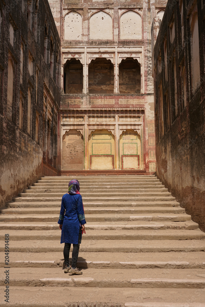 a female tourist standing on a stone ladder in Lahore forte, Pakistan