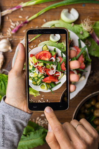 Phone photography of food. Woman hands take photo of lunch with smartphone for social media. Fresh vegetables salad. Raw vegan vegetarian healthy dinner 