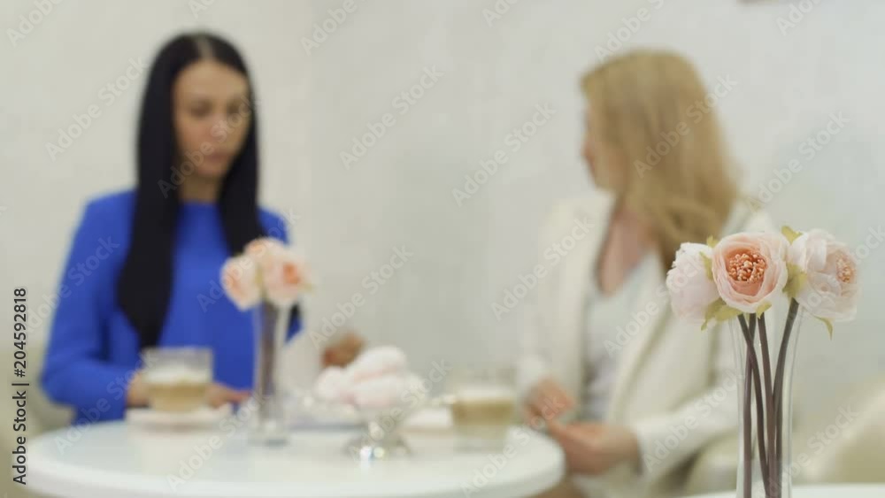 Two businesswomen talks about their new project sitting in cafe Two businesswomen talks about their new project sitting in cafe