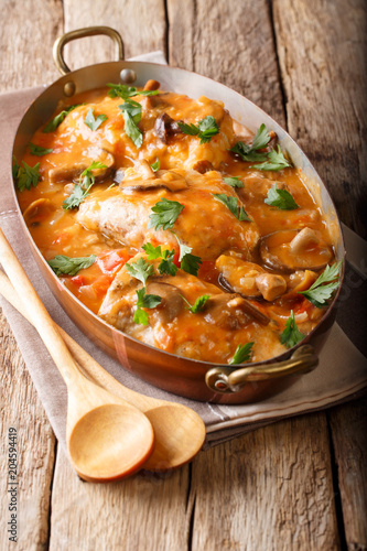 Tasty rustic French food: chicken with mushrooms stewed in sauce close-up. vertical