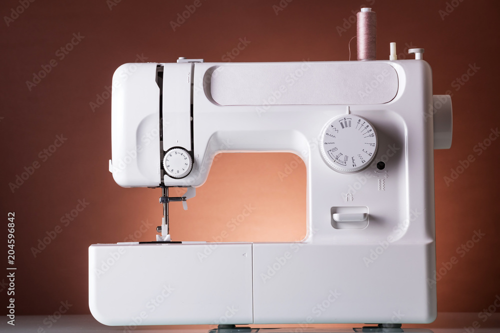 Multi-functional sewing machine, on dark red background