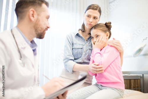 Anxious woman and her daughter listening to doctor opinion about diagnosis during appointment