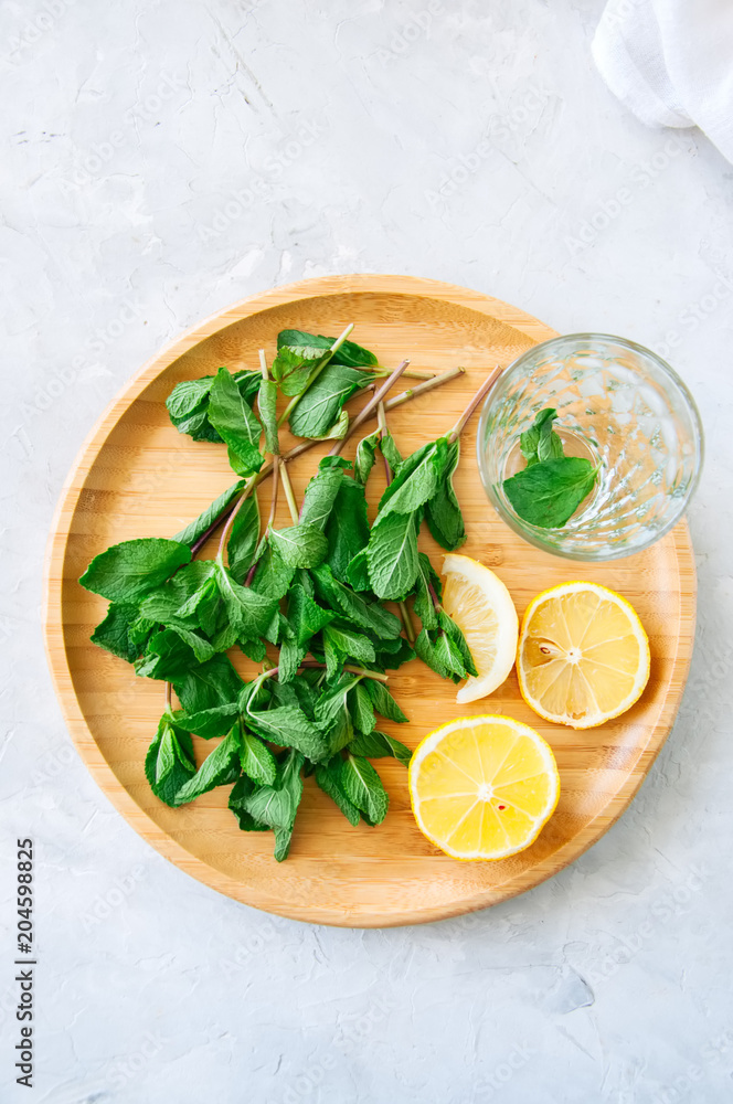 Ingredients for moroccan tea or infused water or mojito. Mint leaves slices of lemon on a wooden plate. White background. Close up. Ingredients for moroccan tea or infused water or mojito. Mint leaves slices of lemon on a wooden plate. White background. Close up.