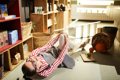 фотографія Young supermarket staff fell down from ladder during work and hit her knee