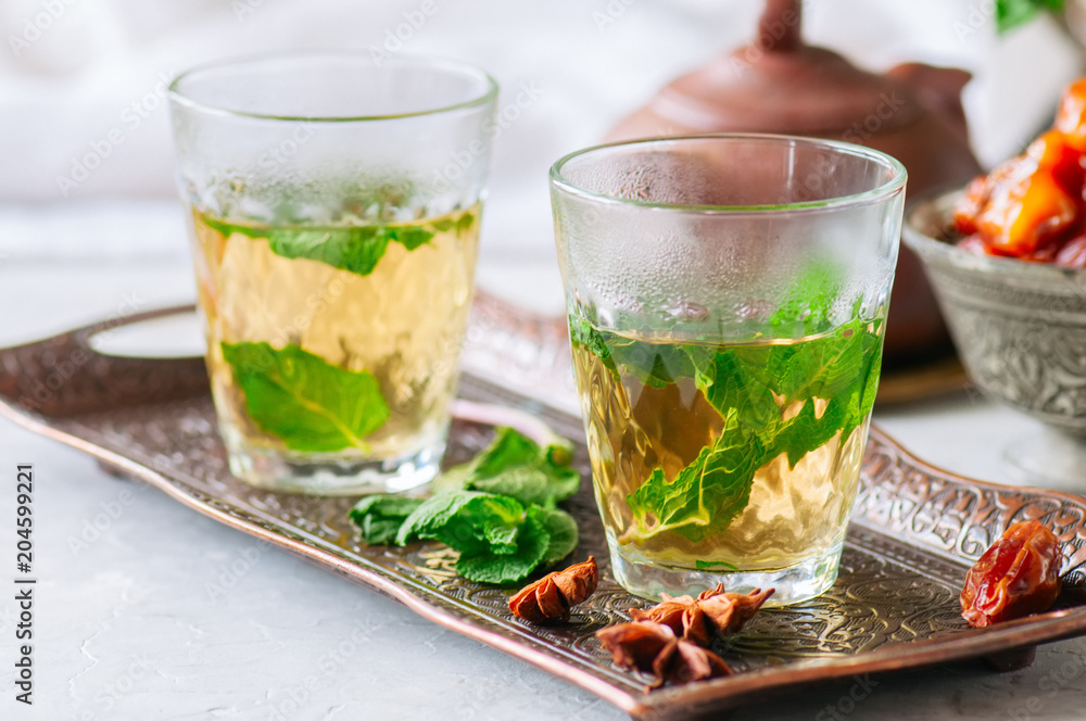 Traditional moroccan mint tea with dates on a vintage tray. White stone background. Traditional moroccan mint tea with dates on a vintage tray. White stone background.