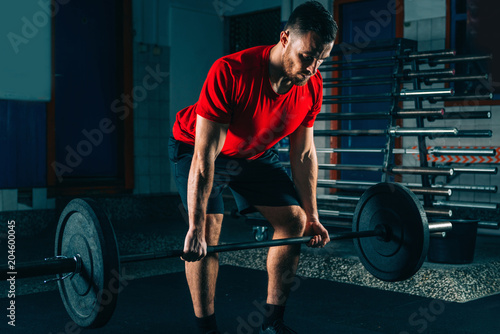 Cross training. Male athlete lifting weights