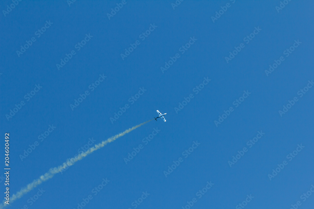 Condensation trace highlighted by the setting sun behind a plane in the blue sky. Condensation track the outdated inversion trail Condensation trace highlighted by the setting sun behind a plane in the blue sky. Condensation track the outdated inversion trail