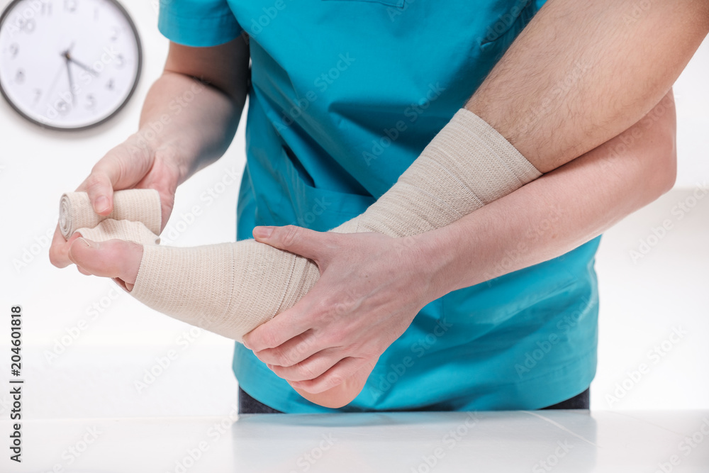 Close-up of male doctor bandaging foot of female patient Close-up of male doctor bandaging foot of female patient