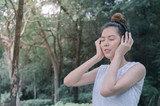 beautiful asian woman smile and relaxing by listen to music from stereo headphones in public park.
