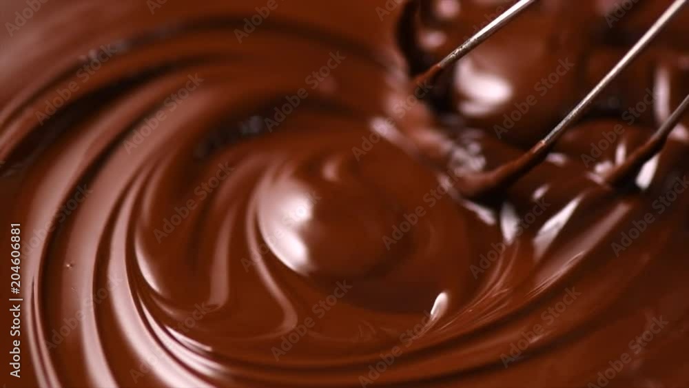 Chocolate. Mixing melted dark chocolate with a whisk. Closeup of liquid hot chocolate swirl. Confectionery. Slow motion 4K UHD video 3840X2160