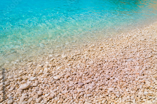 A pebble beach with turquoise waters. Summer holidays concept. photo