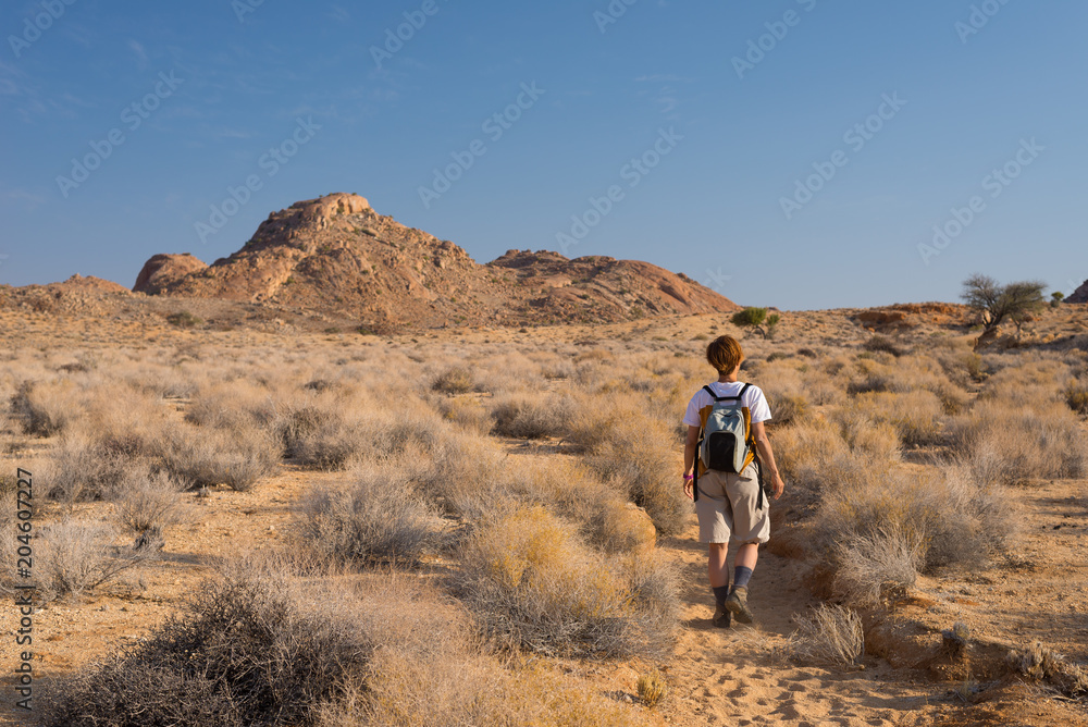 One person hiking in the Namib desert, Namib Naukluft National Park, Namibia. Adventure and exploration in Africa. Clear blue sky.