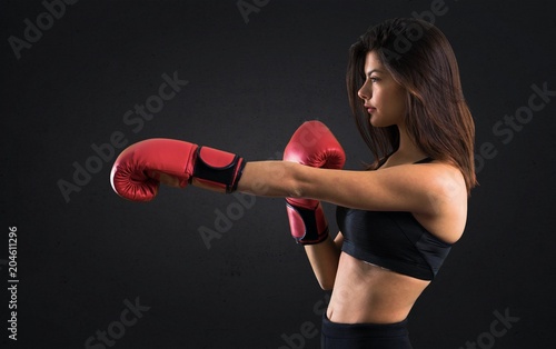 Young sport girl with boxing gloves on black background