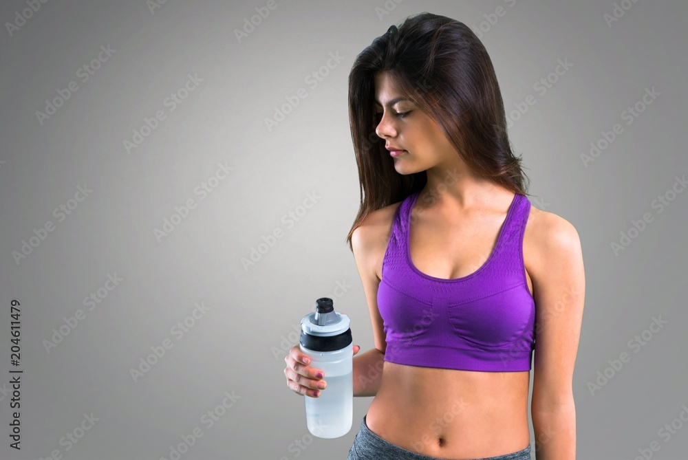 Young sport girl with a bottle on grey background Young sport girl with a bottle on grey background